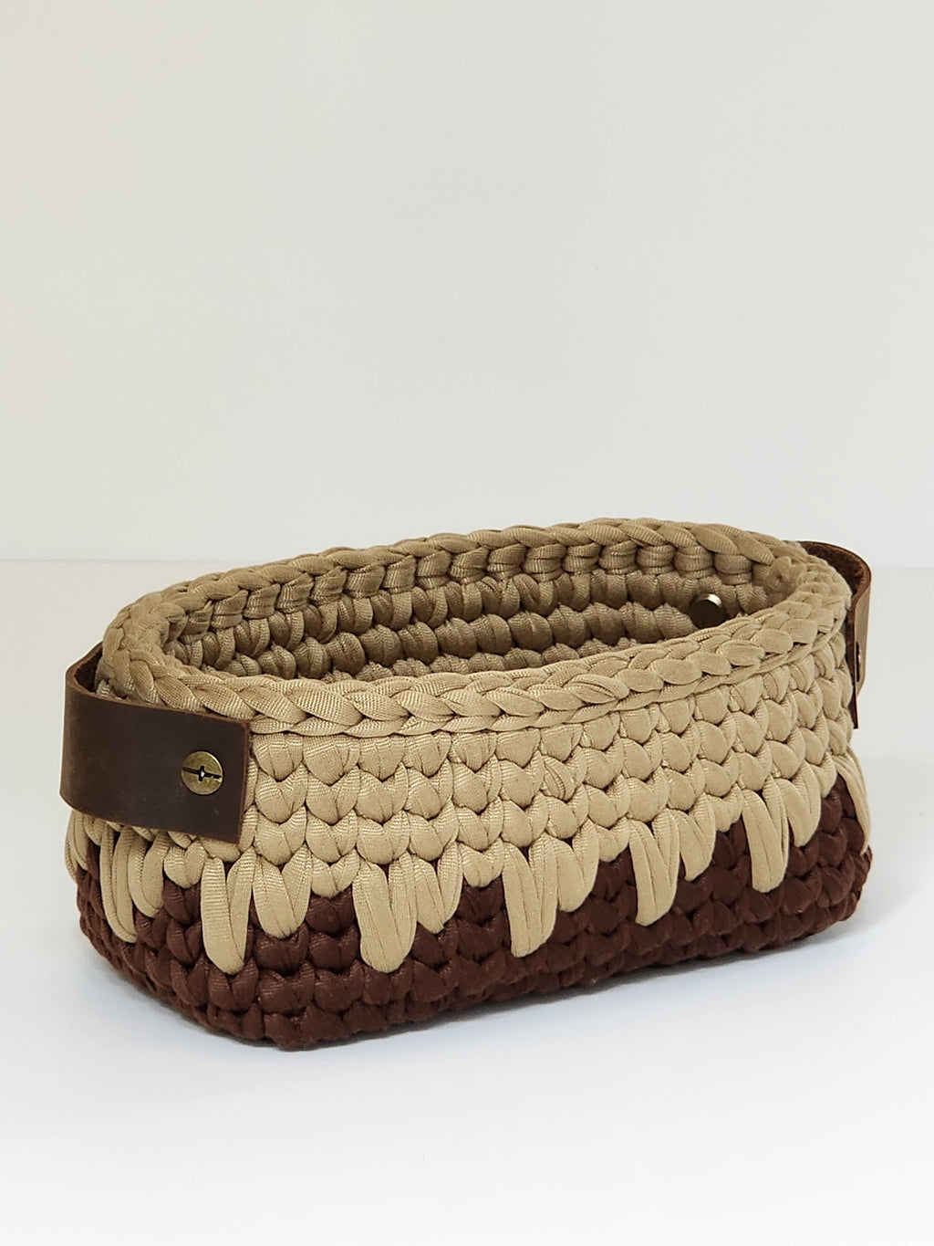 Woven basket with brown and beige pattern on a white background