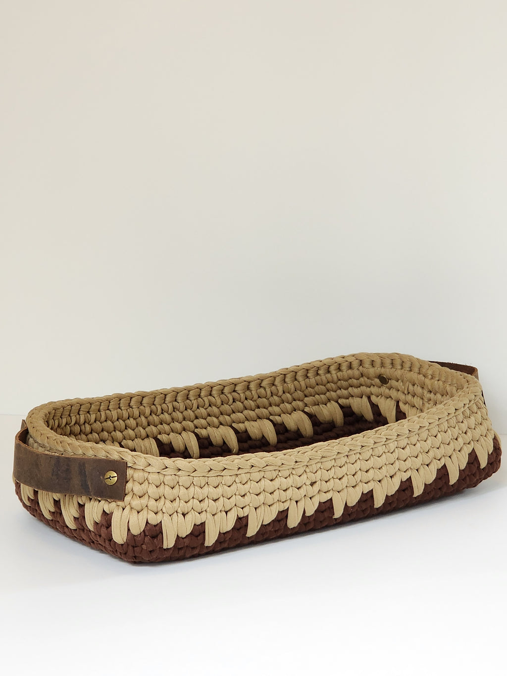 Brown and beige woven basket on a white background