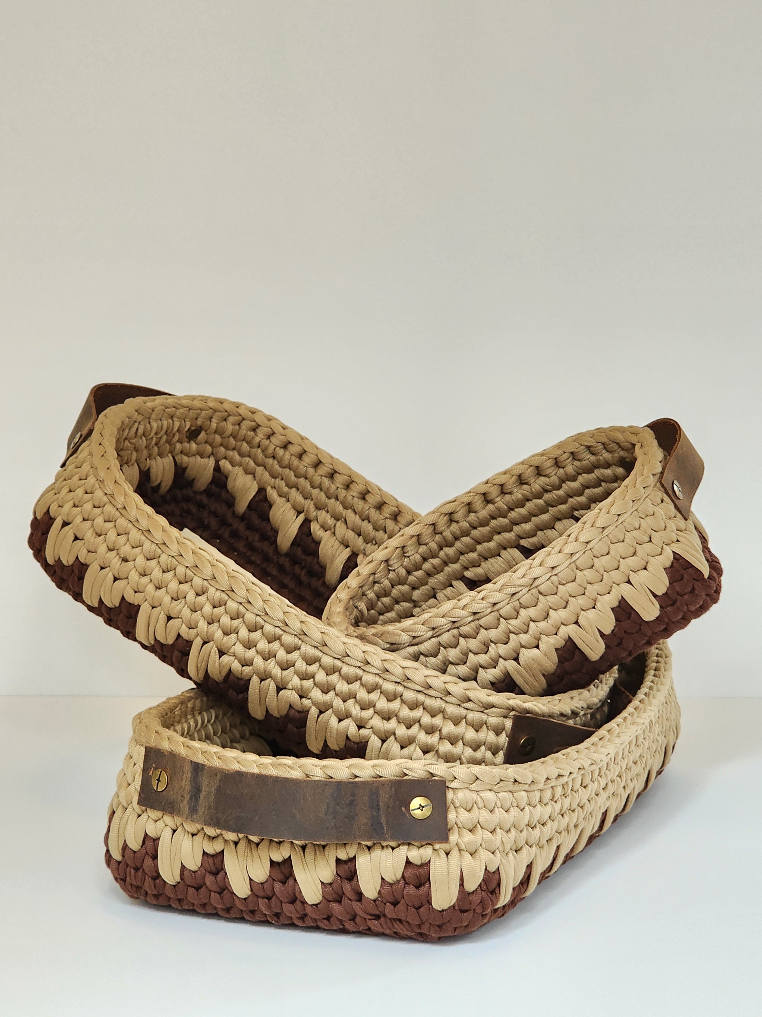 Beige woven baskets with brown straps on a white background
